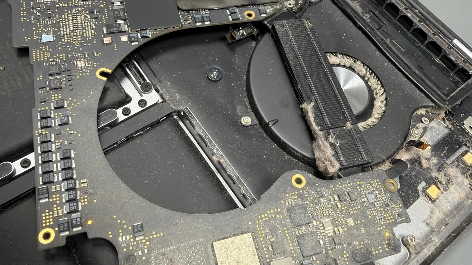 Nadzvednutá deska MacBooku Pro 16 a ventilátor zanesený prachem