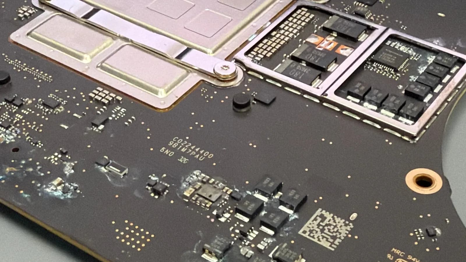 Deska MacBooku Pro 14 po pádu do vody s bílými stopami oxidace