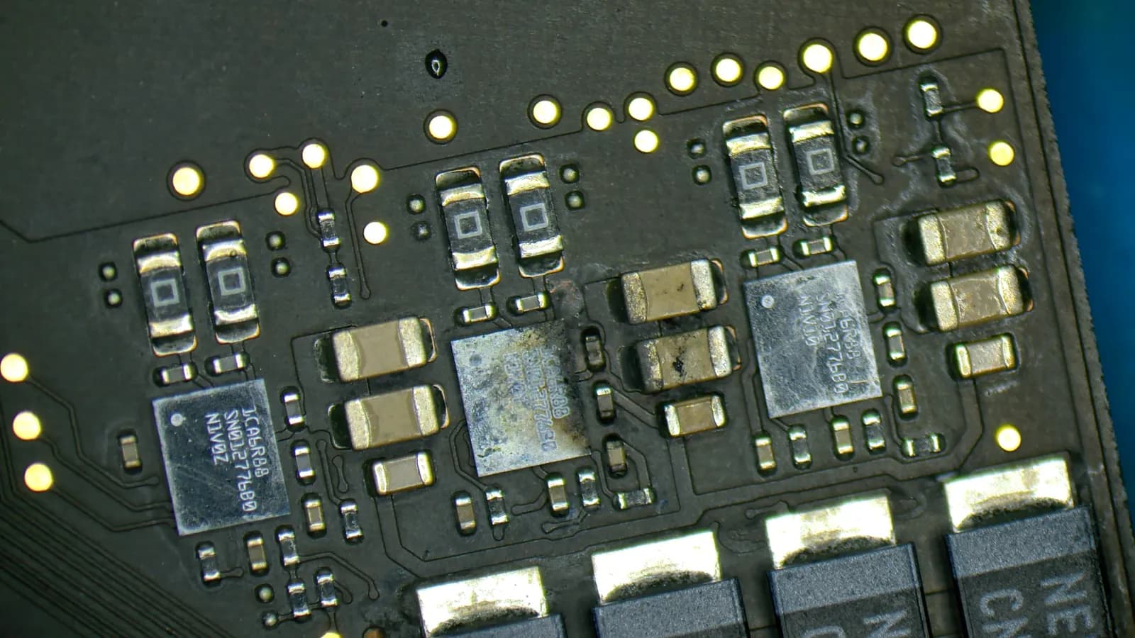 Zbytky oxidace na čipech desky MacBooku Pro 16 po polití