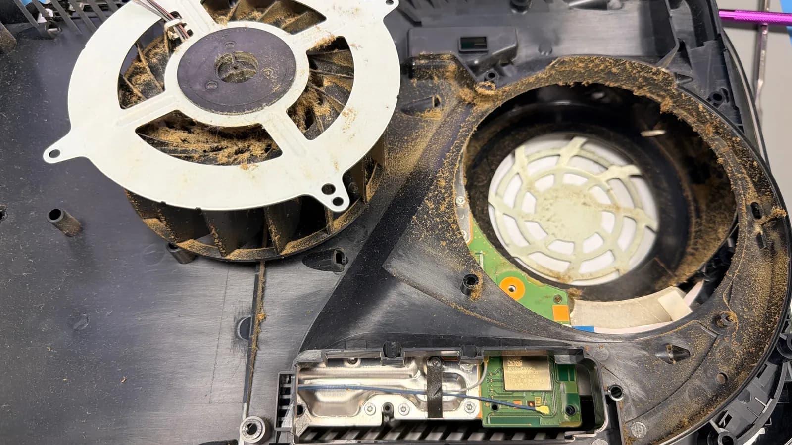 Rozebraná PlayStation 5 s ventilátorem a sáním zaneseným prachem
